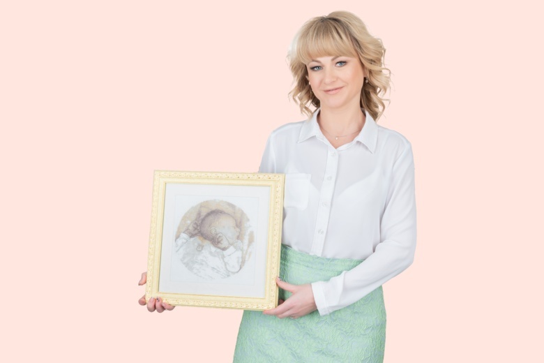 Наталья Воронова, ведущий репродуктолог «Клиники Пасман» с картиной, которую ей подарила пациентка — эту вышивку она сделала 10 лет назад и дала зарок подарить ее доктору, который сможет помочь ей родить ребенка